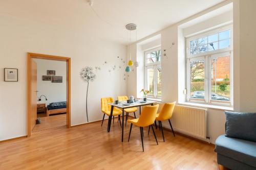 a living room with a dining room table and yellow chairs at Am Kanonenberg in Quedlinburg