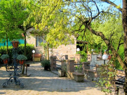 a garden with benches and a building and trees at Tuscan Charm Frassini Cottage in Chiusdino