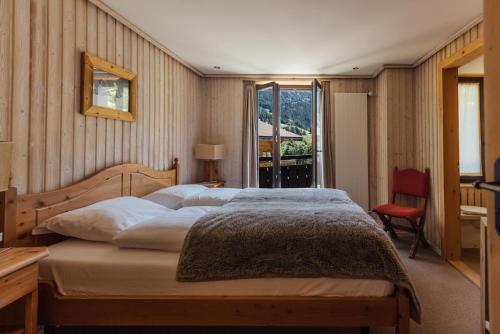 ein Schlafzimmer mit einem großen Bett und einem Fenster in der Unterkunft Hotel Sanetsch in Gsteig