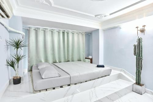 a white bedroom with a bed and a cactus at H2T Hotel Center BuiVien in Ho Chi Minh City
