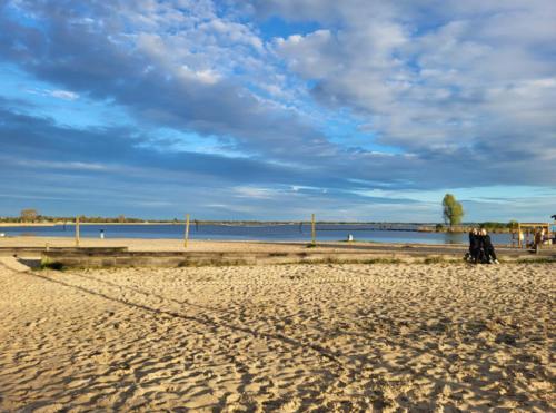 a group of people walking on a sandy beach at Chalet Meerwijck mit Terrasse am Wasser und Meer mit Schwimmbad in Kropswolde