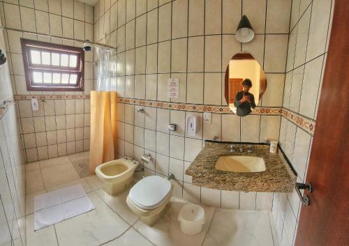 a person taking a picture of a bathroom with a toilet and sink at Casa Maré Floripa - Coliving, Coworking & Community in Florianópolis