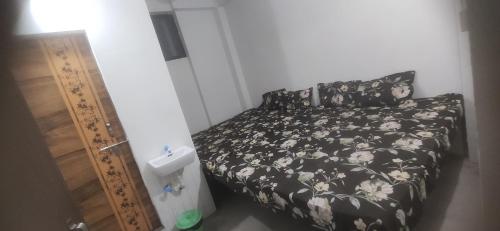 a bedroom with a bed with a black and white comforter at Shree Shyam Guest House in Nagpur