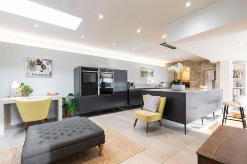 a kitchen with black cabinets and a table and chairs at Cotswold Hillside Retreat with Stunning Views in Nailsworth