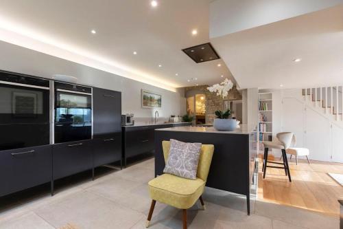 a kitchen with black cabinets and a yellow chair at Cotswold Hillside Retreat with Stunning Views in Nailsworth