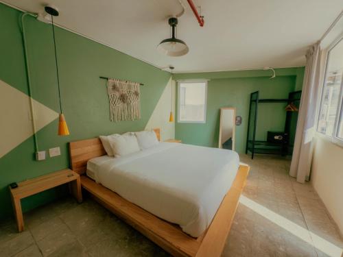 a bedroom with a white bed and a green wall at Viajero Casco Viejo Hostel in Panama City