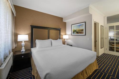 a large bed in a hotel room with two lamps at Best Western Plus Palm Court Hotel in Davis