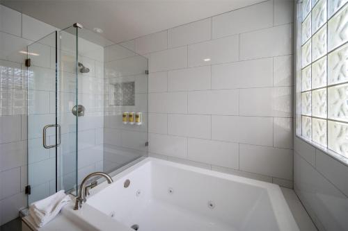 a white bathroom with a tub and a window at Best Western Plus Palm Court Hotel in Davis
