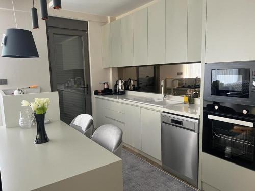 a kitchen with white cabinets and a vase of flowers on a counter at Greenpark Villas in Kemer