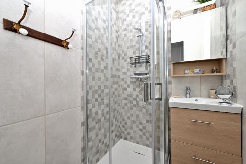 Un baño con ducha de cristal y lavabo. en Maison L'Arénoulat, en Aspet
