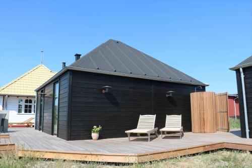 a black shed with two chairs on a wooden deck at 0090-Romo-Lakolk-256 in Lakolk