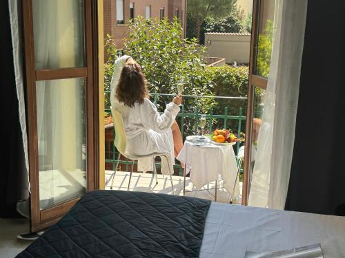 a woman sitting on a chair on a balcony at Relais Stibbert Florence in Florence