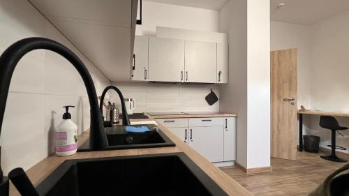 a kitchen with white cabinets and a sink at Velo Hostel - Campers & Bikes ENERGYLANDIA in Okleśna