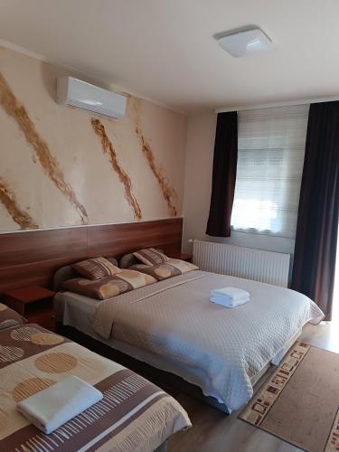 a bedroom with two beds and a window at Boglárka Vendégház in Mosonmagyaróvár