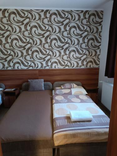 a bed in a room with a wall at Boglárka Vendégház in Mosonmagyaróvár