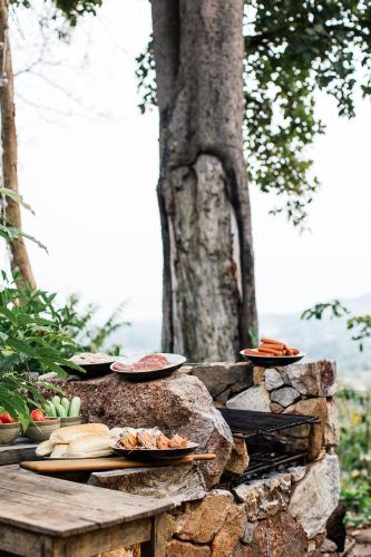 a table with plates of food on a stone wall at Payana Kampot in Kampot