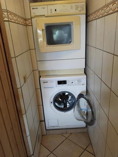 a washer and dryer in a bathroom with a microwave at Dejligt og stort hus med spa og sauna in Roslev