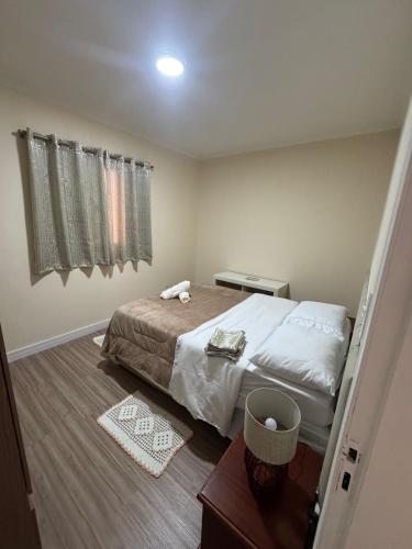 a bedroom with a bed and a table and a window at Apto Mobiliado 15 m Aero Gru Garagem in Guarulhos