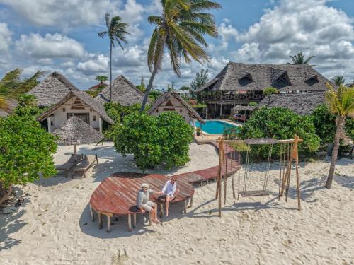 two people sitting on a swing on the beach at a resort at Juana Ocean Villas in Makunduchi
