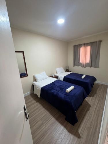 a bedroom with two beds with blue sheets and a window at Apto Mobiliado 15 m Aero Gru Garagem in Guarulhos