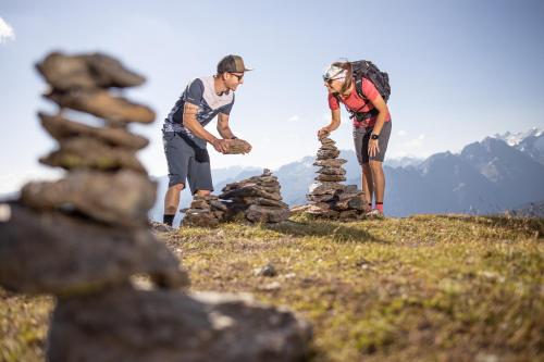 two people on a hill with a stack of rocks at Ferienhotel Sonnenhof in Zell am Ziller