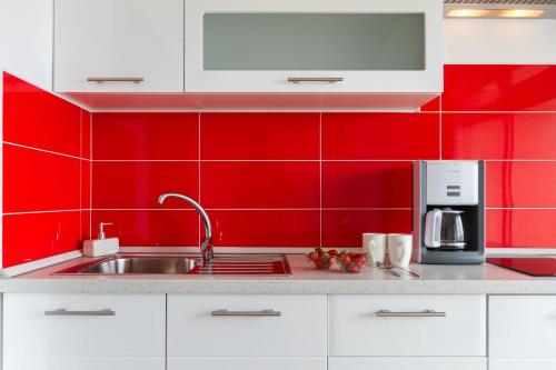 a red kitchen with a sink and a microwave at Apartments and Rooms Bonkan Hvar in Hvar