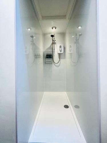 a bathroom with a shower with white walls and a shower at The Green Room in Tideswell
