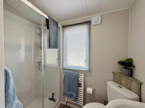 a bathroom with a toilet and a glass shower at Kindred, a relaxed coastal escape in Swanage, Dorset with 300mbps WiFi in Swanage