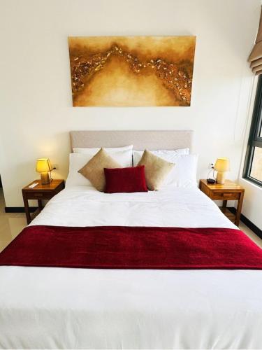 a bedroom with a white bed with a red blanket at YAKA Trizen Luxury Apartments - 53rd and 51st Floor with Stunning Views in Colombo