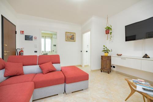a living room with a red couch and a tv at A1 Fiori di Pesco #TRILOCALE DOPPI SERVIZI- Fiera Rho Milano Monza Como Malpensa in Cesate
