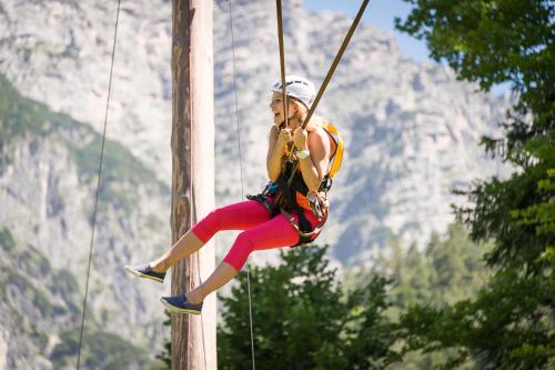 a woman on a rope swing in the mountains at Hotel Gut Brandlhof in Saalfelden am Steinernen Meer