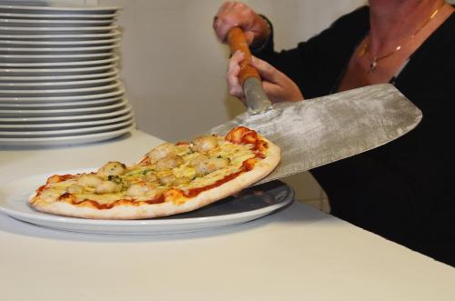 a person cutting a pizza on a plate on a table at Hotel Fortin in Anost