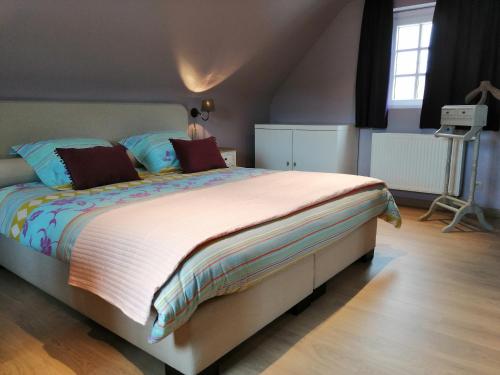 a bedroom with a large bed with colorful sheets and pillows at Cozy Holiday Home in Aalter near Lake in Maria Aalter