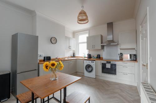 a kitchen with a table with a vase of flowers on it at Parkstone Central by Grandeur Property in Parkstone