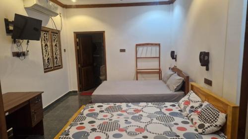 a bedroom with a bed and a desk and a television at RS Mahal in Jaffna