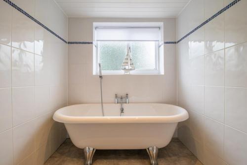 a white bath tub in a bathroom with a window at Cairnhill House - cosy 3 bedroom in Airdrie