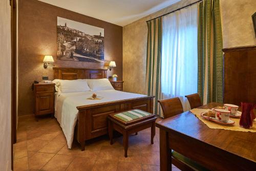 a hotel room with a bed and a table and a desk at Casanova - Wellness Center La Grotta Etrusca in San Quirico dʼOrcia