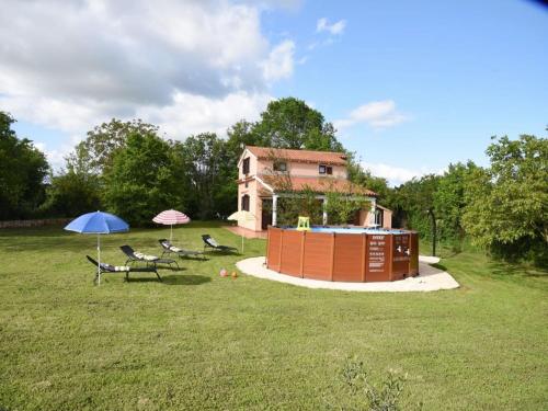 a house with chairs and an umbrella in a field at Charming Pool Home Near Pula in Pula