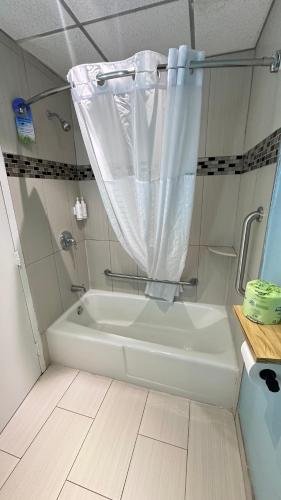 a white bath tub with a shower curtain in a bathroom at Days Inn by Wyndham Southington in Southington