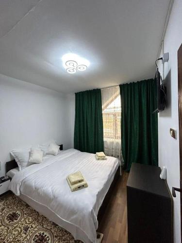 ein Schlafzimmer mit einem großen weißen Bett und grünen Vorhängen in der Unterkunft Casa Sofia in Murighiol