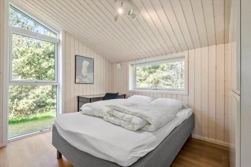 a bedroom with a bed with white sheets and two windows at 0122-Romo-Smafolksvej-44 in Høm