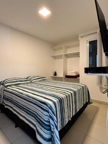 a bedroom with a bed with a striped blanket at Apto Cittá in Brasília