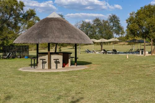 a hut with a table and chairs in a field at Lembah Kali Riverside Estate by Euphoric Leisure in Lanseria