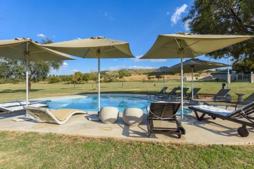 a swimming pool with chairs and umbrellas at Lembah Kali Riverside Estate by Euphoric Leisure in Lanseria