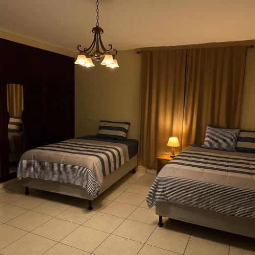 a bedroom with two beds and a chandelier at Go Bed & Breakfast in San Pedro Sula