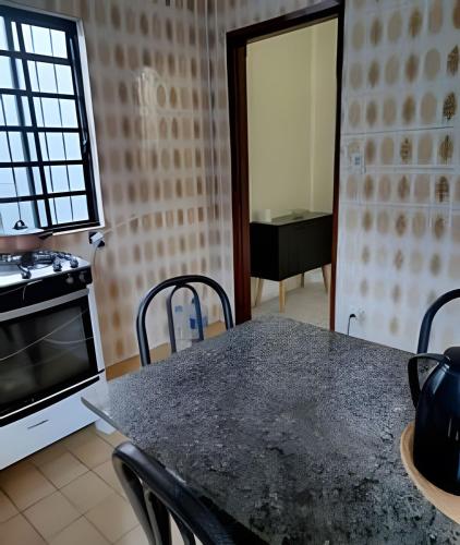 a kitchen with a table with chairs and a stove at Refúgio Hostel Unidade 3 in Bauru