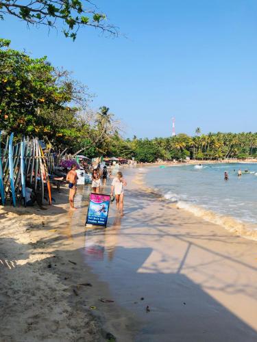 a group of people walking on a beach at Devon Surf . Inn - Hiriketiya in Dickwella