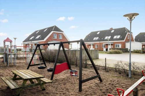 a playground with two swings and a bench and houses at 0332-Romo-Sonder-Frankel-38 in Havneby