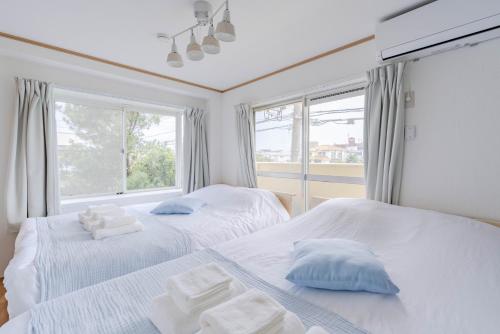 two beds in a room with two windows at IJIRIGoodStay in Fukuoka