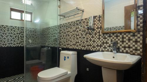 a bathroom with a toilet and a sink and a shower at Seven Springs Plantation Resort in Munnar
